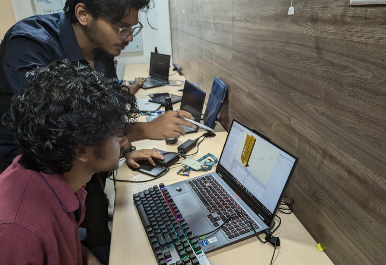 Two team members reviewing a 3D model of the kiosk hardware on a laptop